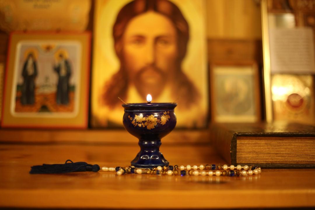 Kristus-ikoni taustalla ja sen edessä palava lampukka sekä pöydällä oleva rukousnauha