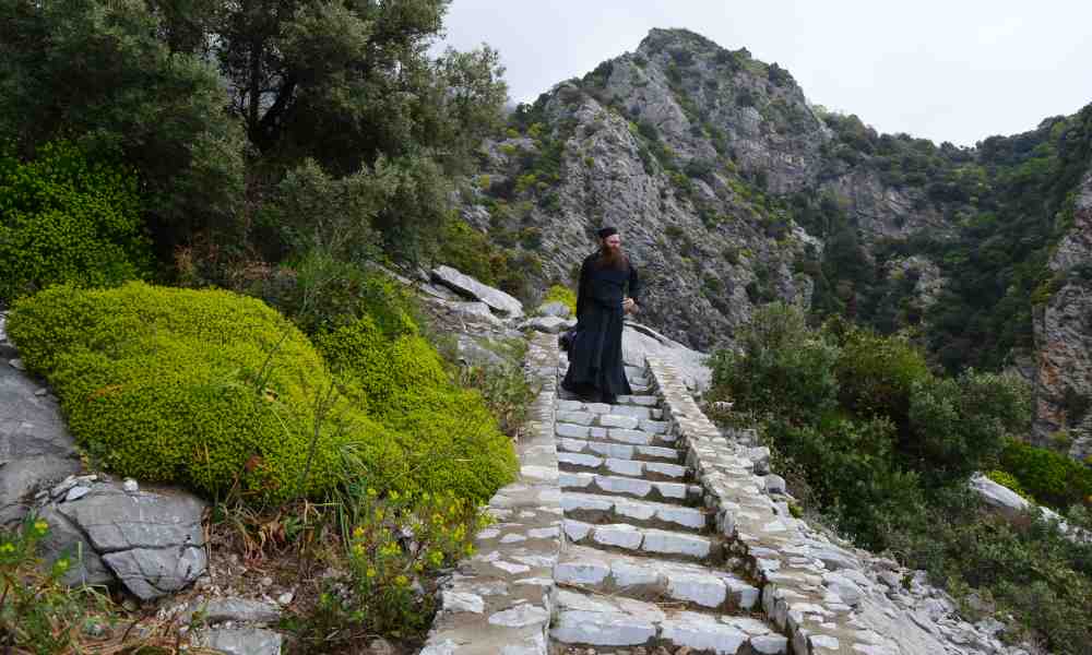 Pappismunkki Damaskinos Ksenofontoslainen laskeutuu kivisiä rappusia pitkin alas vuorenrinnettä Athos-vuorella Kreikassa