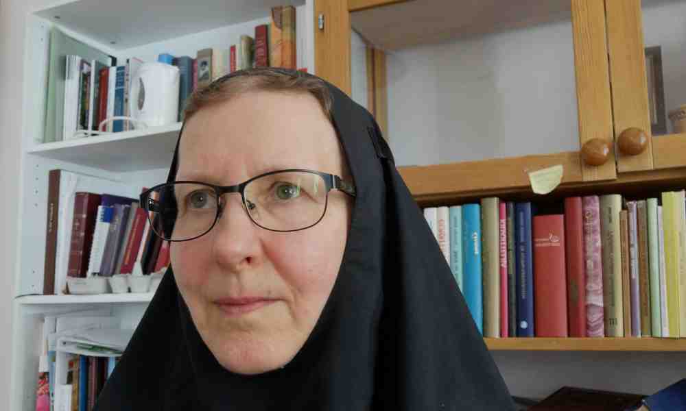 Lintulan nunna Ksenia seisoo kirjahyllyn edessä mustassa nunnan asussa