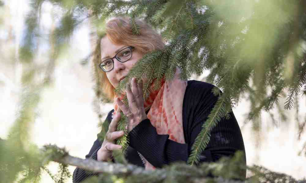 Runoilija Aurora Tinja Eronen kurkistaa puiden siimeksestä