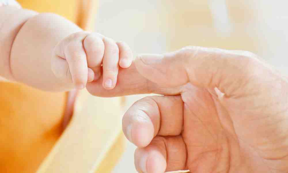 Vauvan ja aikuisen kädet tarttumassa toisiinsa